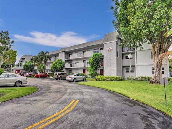 Front view of a multi-story apartment building with parking area.