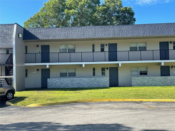 Front view of a two-story apartment building with black railings and a sloped roof.