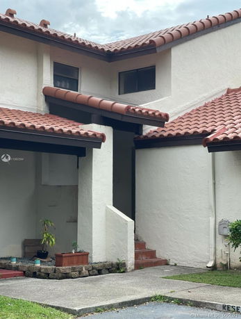 Front view of a two-story house with tiled roof and entrance steps.