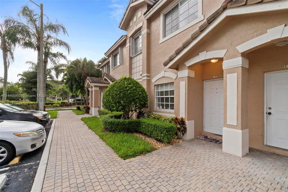 Front view of a multi-story townhouse with arched entrances and tile roof.