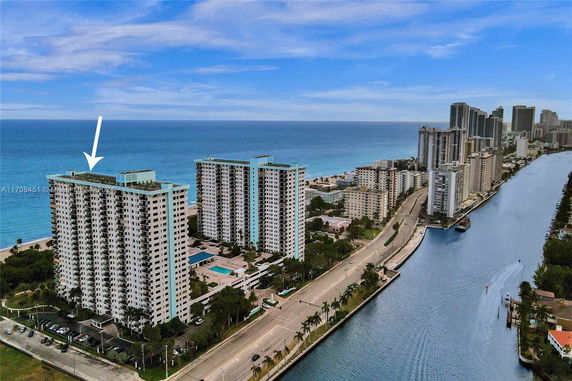 Panoramic view of high-rise buildings along a waterfront with an ocean backdrop.