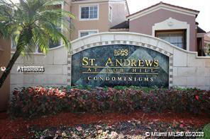 Front view of a condominium entrance sign with adjoining buildings in the background.
