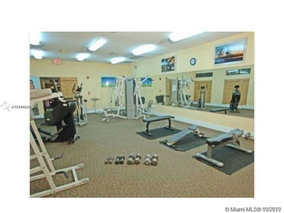 Indoor gym area with exercise equipment, benches, and mirrors.