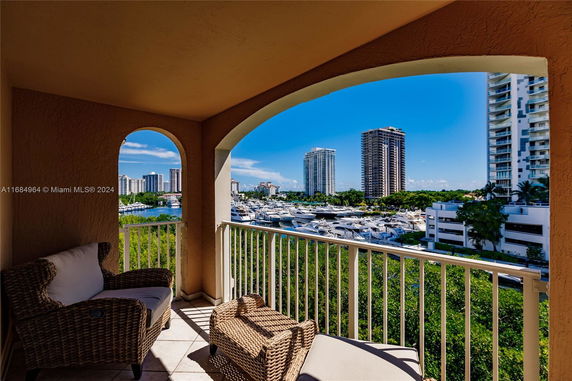 Balcony view overlooking a marina and tall buildings under a clear blue sky.