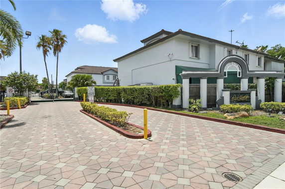 Front view of a residential complex entrance with a decorative archway and driveway.