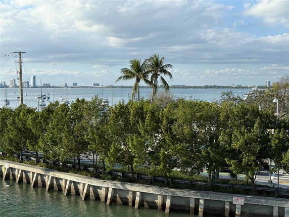View of a waterfront area with trees, boats, and a bridge in the distance.