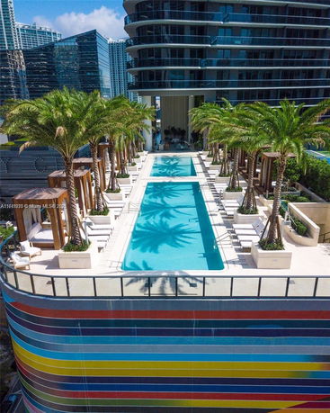 Rooftop swimming pool area with palm trees and lounge chairs.