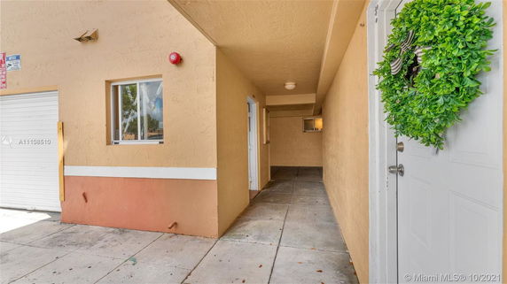 Entrance view of a building with a narrow walkway and a door adorned with a green wreath.
