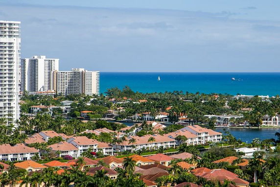 View of a coastal cityscape with multiple residential buildings and skyscrapers, overlooking the ocean.