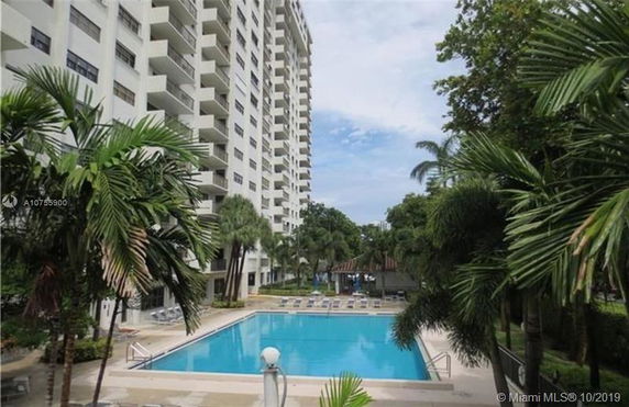 Swimming pool area in front of a tall residential building.