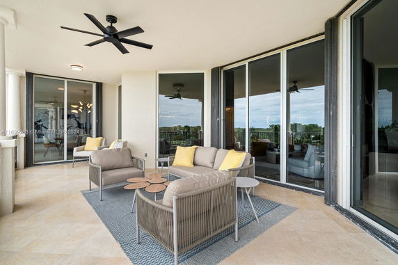 Outdoor seating area on a balcony with glass doors and overlooking the landscape.