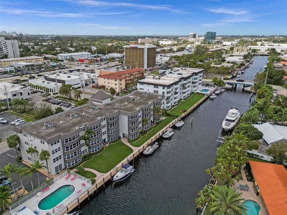 Aerial view of canalside residential buildings with multiple windows and a central swimming pool, surrounded by urban infrastructure.
