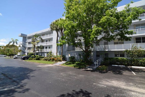 Front view of a multi-story building with balconies and parking area.