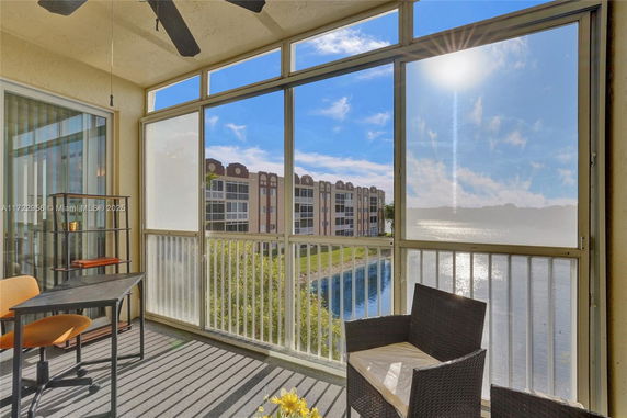 View from a balcony with chairs and a table overlooking a lake and apartment buildings.