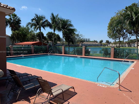 Outdoor swimming pool with lounge chairs and palm trees surrounding the area.
