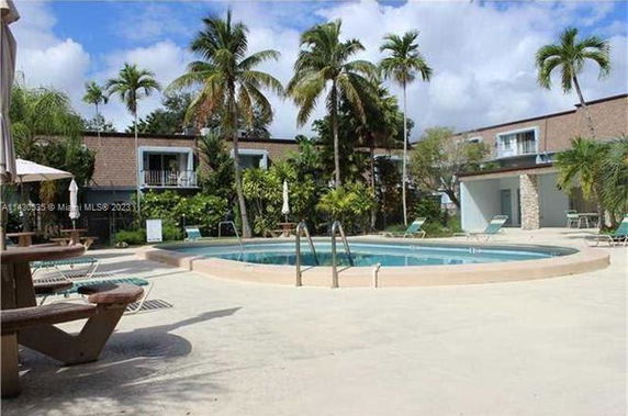 Outdoor swimming pool surrounded by lounge chairs and palm trees.