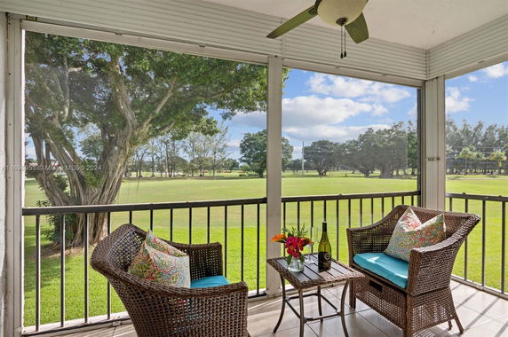 View from a covered balcony overlooking a grassy outdoor area with trees.
