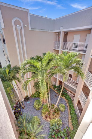 View of an outdoor courtyard area with plants and balconies in a multi-level building.