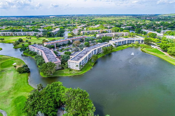 Aerial view of residential buildings surrounded by water and greenery.