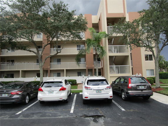Parked cars in front of a multi-story apartment building.
