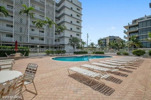 Front view of a multi-story building with balconies and a pool area.