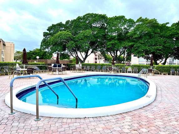 Outdoor swimming pool with surrounding patio and trees.