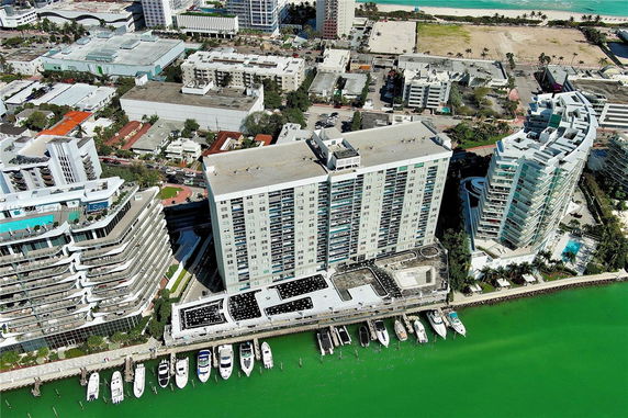 Aerial view of high-rise buildings with visible rooftops featuring mechanical units and a dock with boats.