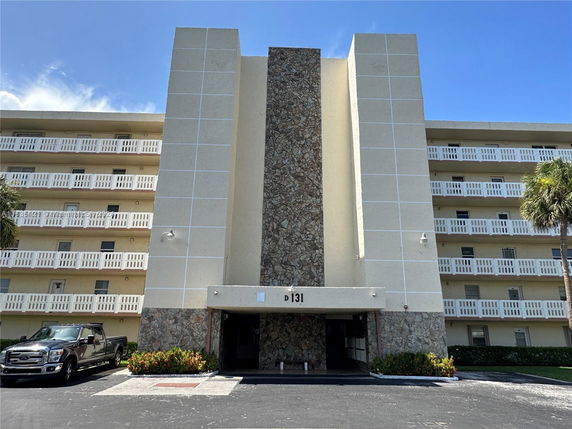 Front view of a multi-story building with a central stone accent and exterior balconies.