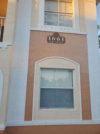 Partial view of a building facade with an address plaque reading 1661 S.E. 28 St.