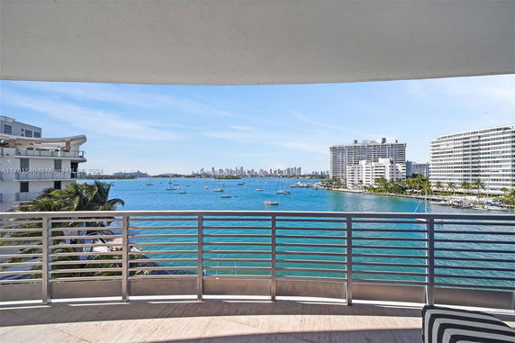 View of a waterway with boats and distant city skyline from a balcony.