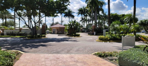 Entrance view of a landscaped area with palm trees and a small building.