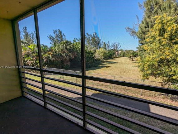 View from a balcony showing a large grass field and trees.