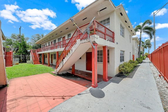 Front view of a two-story building with external red staircases and a red railing.