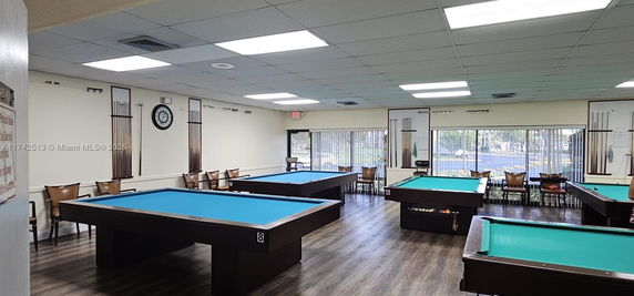 Room with several billiard tables and chairs along the walls.