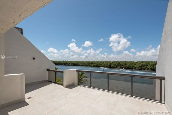 Balcony view overlooking a river with a distant tree line and boat visible.