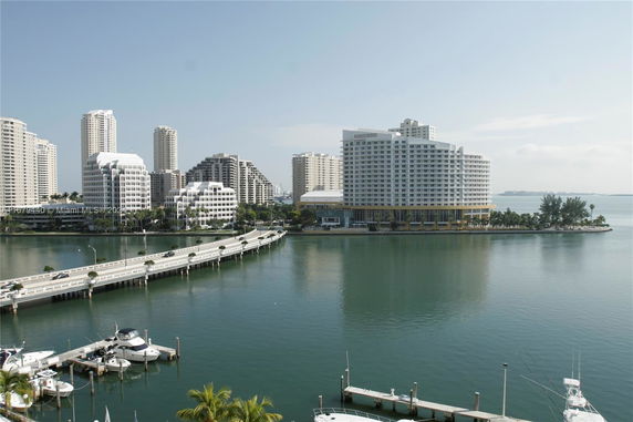 View of high-rise buildings and a bridge over water with boats docked nearby.