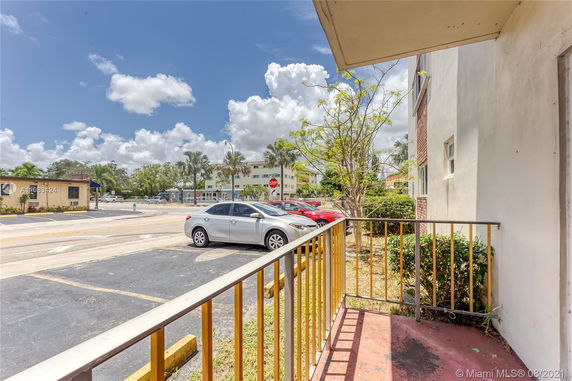 View from a building showing a parking area with several cars parked and street view.