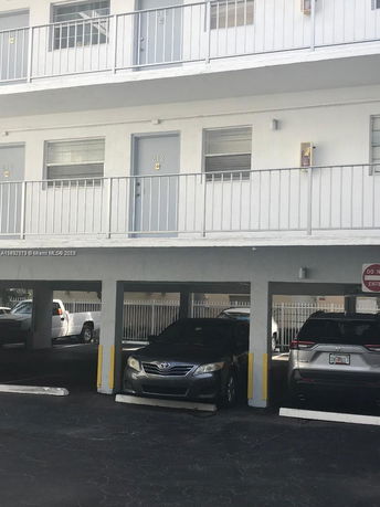 Outdoor covered parking area beneath a building with multiple apartments visible above.
