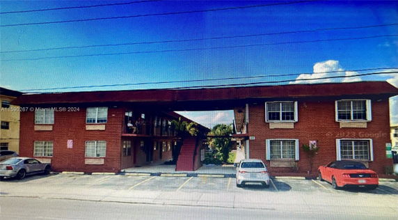 Front view of a two-story red brick building with a central staircase and parking spaces in front.