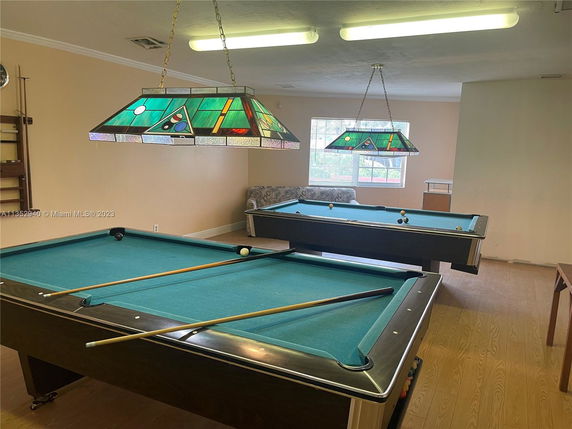 Room with two billiard tables and decorative overhead lights.