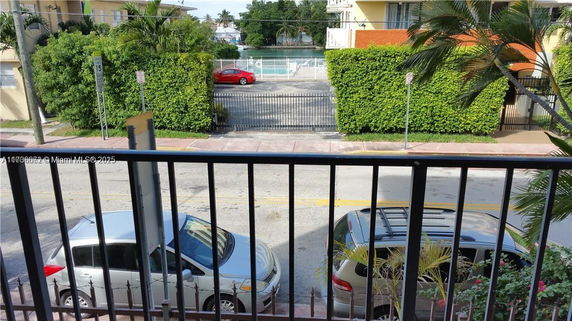 View from a building showing parked cars on the street and a gate leading to a waterway or canal.