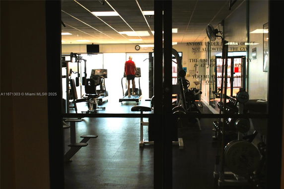 Indoor gym area with exercise equipment and a person using a treadmill.