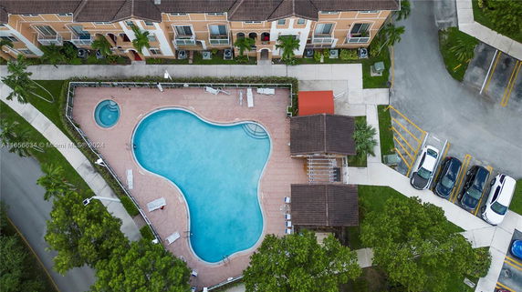 Aerial view of a swimming pool area adjacent to a row of residential buildings.
