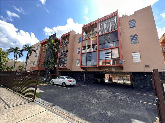 Front view of a multi-story residential building with a parking space below.