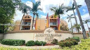 Front view of a multi-story building with palm trees and a sign reading 'Mediterranean'.