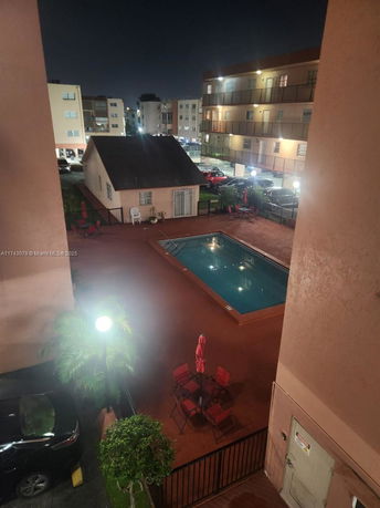 Night view of an outdoor swimming pool area surrounded by multi-story apartment buildings.