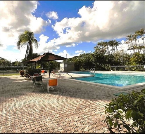Outdoor swimming pool area with seating and umbrellas.