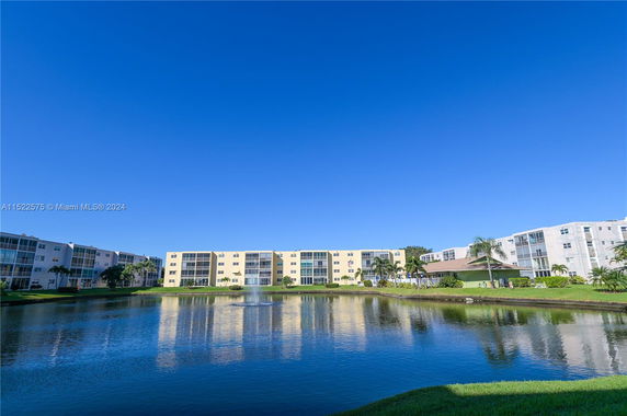 View of a multi-story residential complex near a pond.