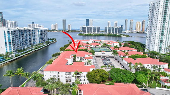 Aerial view of buildings surrounded by water and high-rise structures in the background.