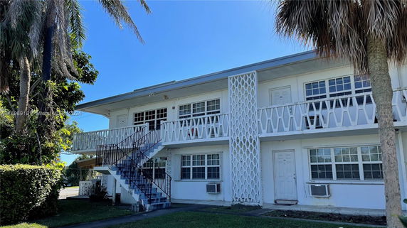 Front view of a two-story building with exterior stairs and balcony.